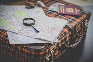 Map with a magnifying glass on top of a suitcase magnify glass