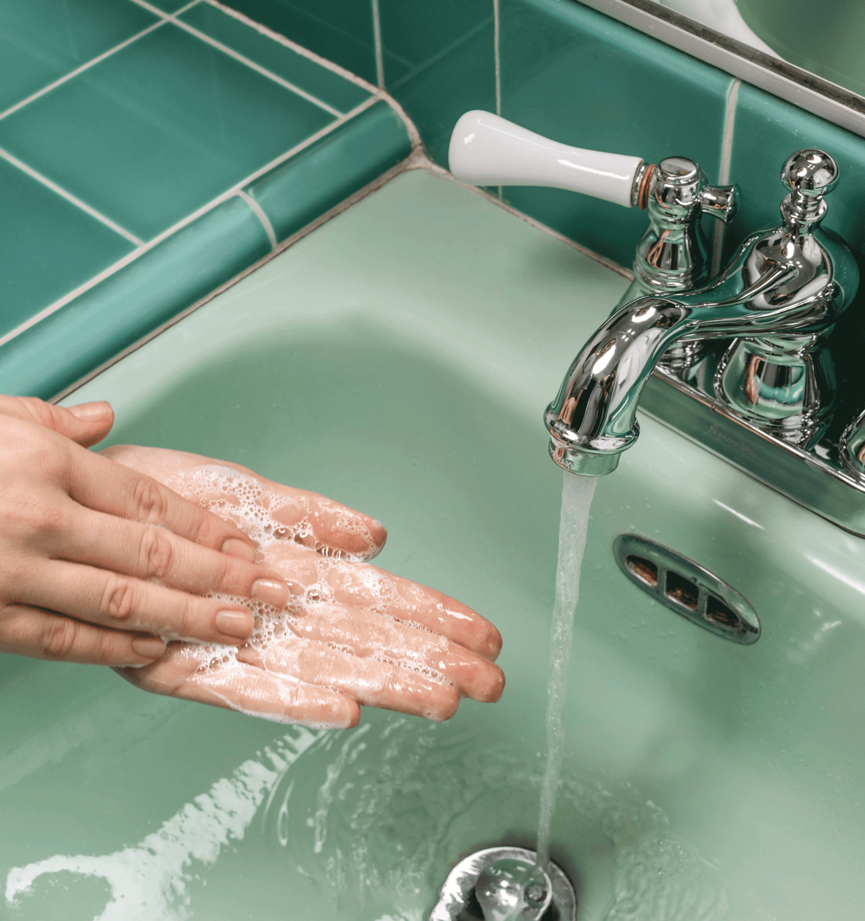 Photo of a person washing their hands with soap in a green ceramic sink Formula Botanica promo photo - handwashing