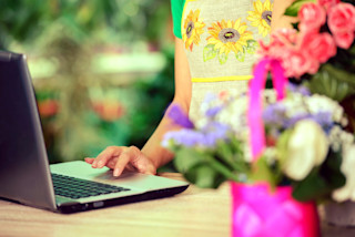 Woman standing at laptop with flowers