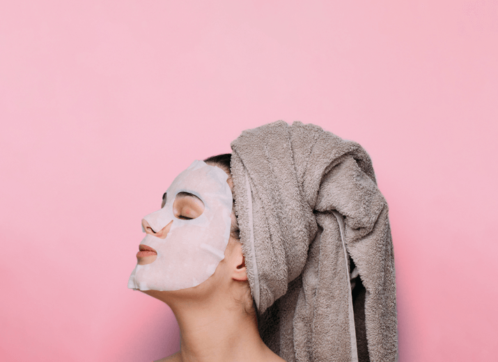 Side profile of a young woman with a face mask on and her hair tied up in a towel Health and Beauty industry page - London Research Infographic