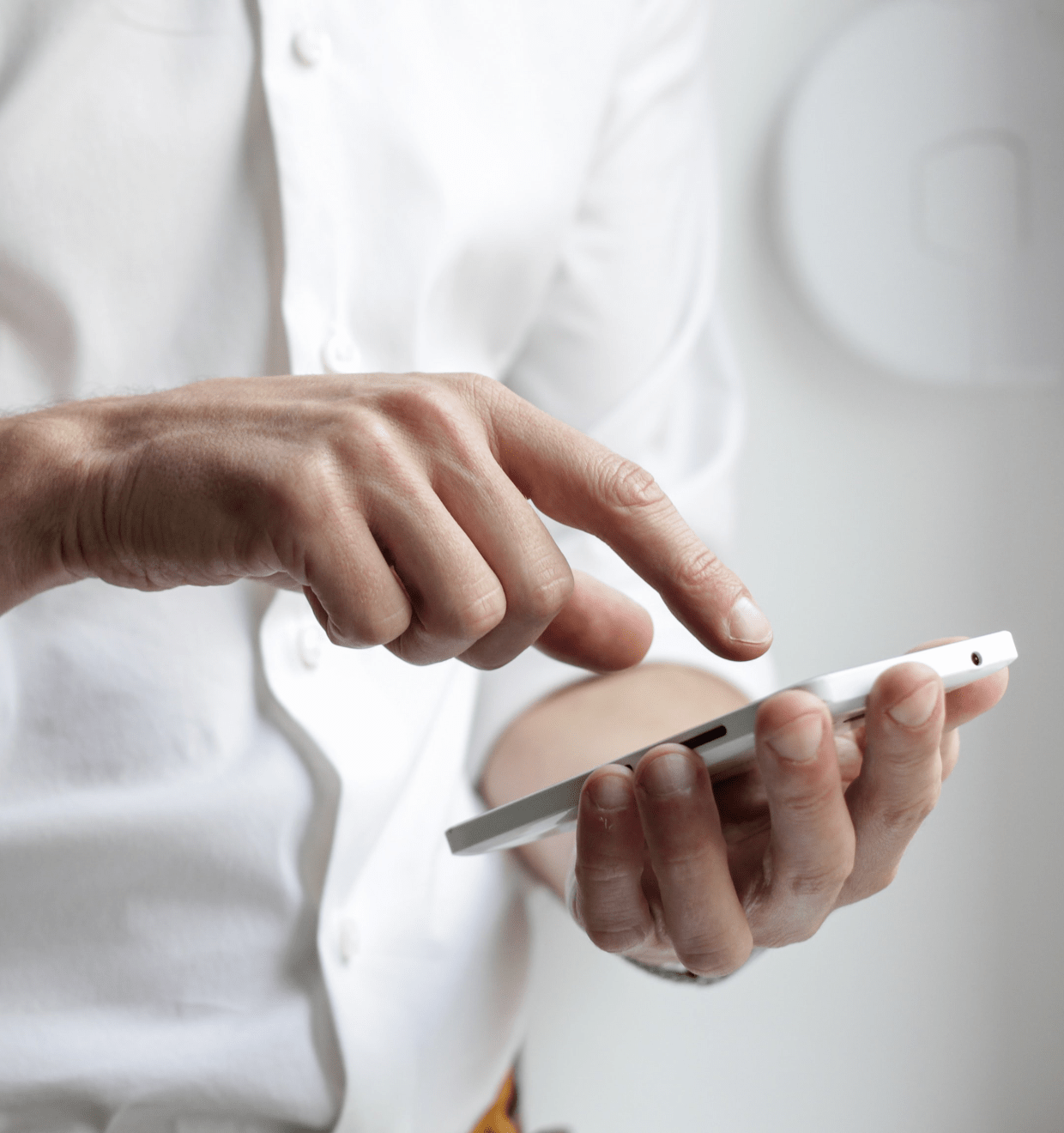 Photo of a man in a white shirt typing something on his smartphone Homebridge promo photo of a man holding smartphone