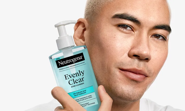 Man with clear skin holding a bottle of Neutrogena® Evenly Clear™ Acne Cleanser, mobile, mobile version.