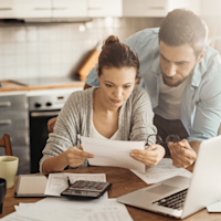 couple at kitchen table looking at paperwork Thumb