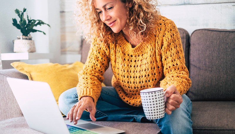 woman in yellow jumper looking at laptop