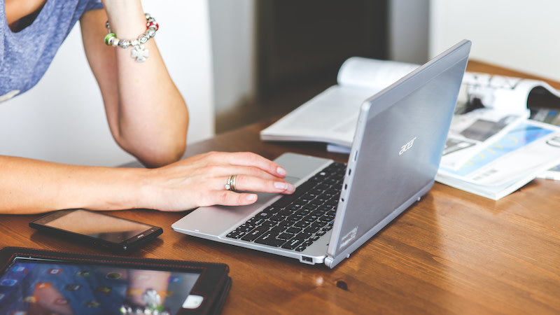 Woman's hand with smartphone and laptop