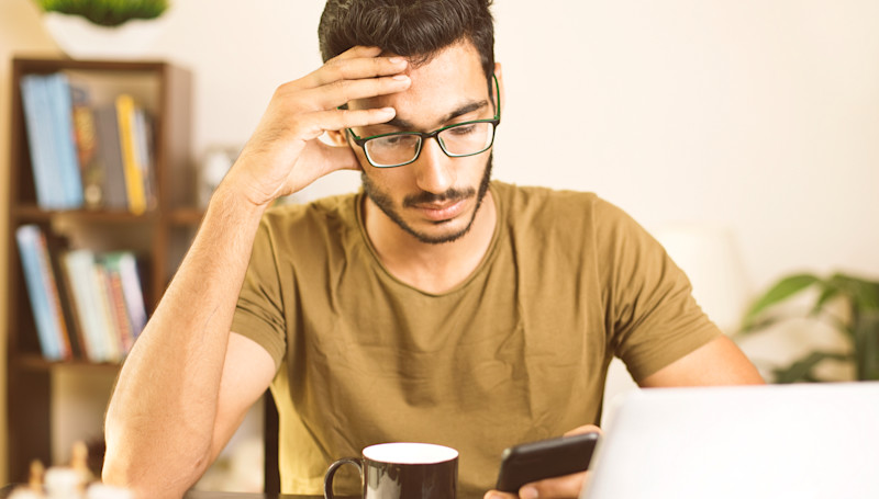Man looking at his phone holding his head