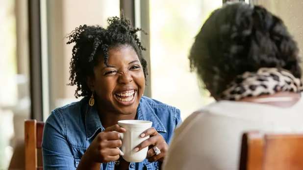 Two people in a cafe talking and laughing.