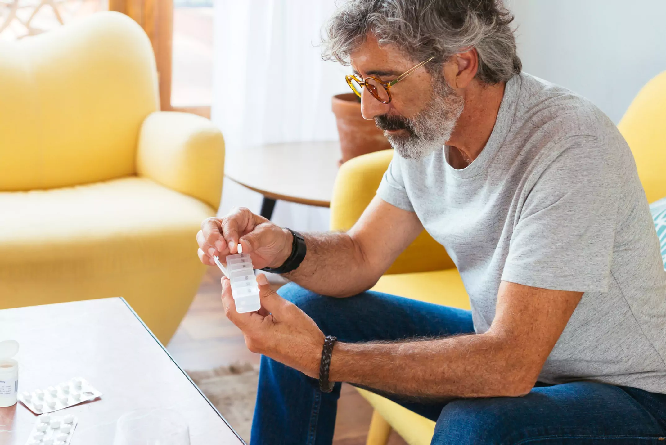 Older man sitting down with a pill container
