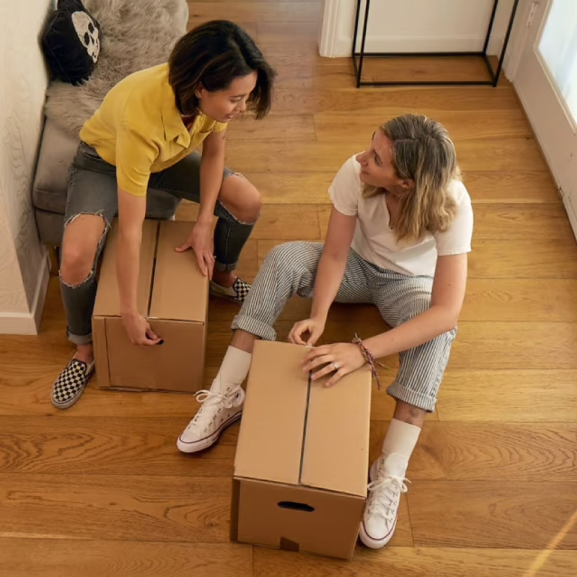 Two women with moving boxes and sneakers