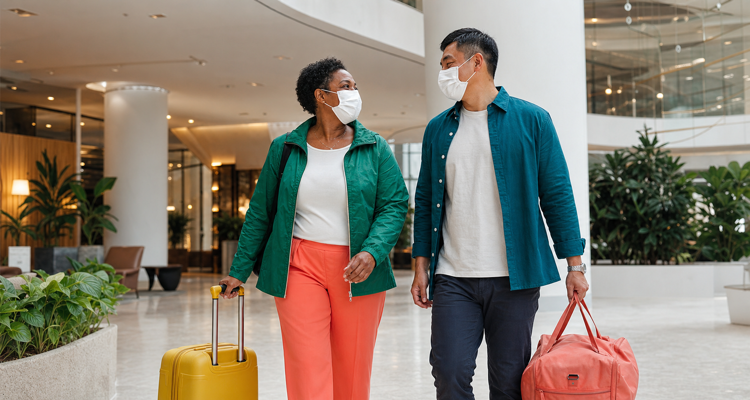 masked-travellers-walking-through-bright-hotel-lobby-750x400