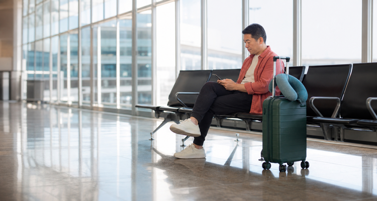 traveller-waiting-at-airport-with-green-suitcase-750x400