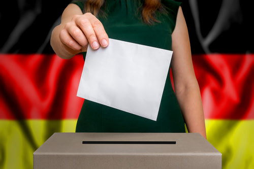 Woman putting her vote in a ballot box, German flag behind her