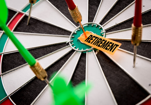 Dart pinning a paper reading "retirement" to a dart board