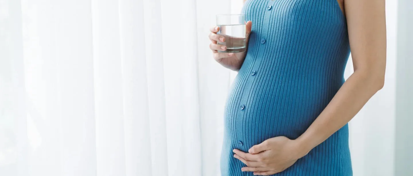 Pregnant mother holding a glass of water.
