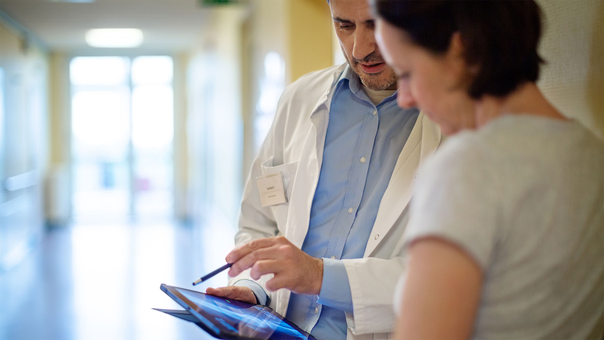 A doctor discusses a diagnosis with a patient using an iPad. The 5G network enables real-time networking and thus helps patients.