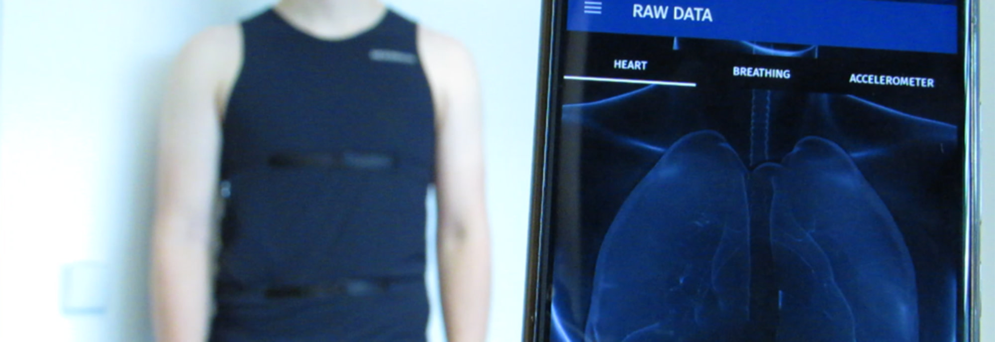 Ein Mann trägt eine EKG-Weste. Die Daten werden auf ein Smartphone übertragen.