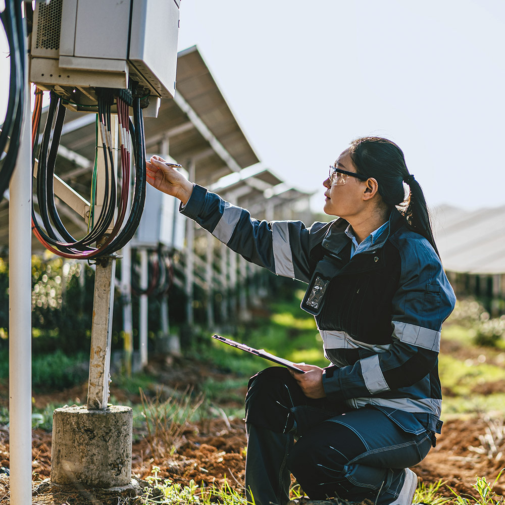 Eine Frau arbeitet am Stromkabel eines Solarpanels.
