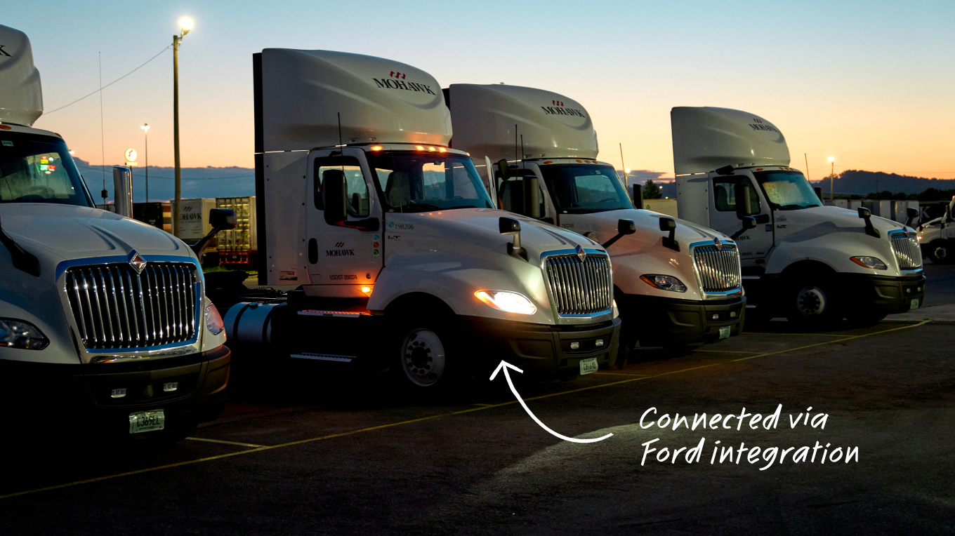Row of white Mohawk semi-trucks parked at dusk, with text "Connected via Ford integration" overlaid.