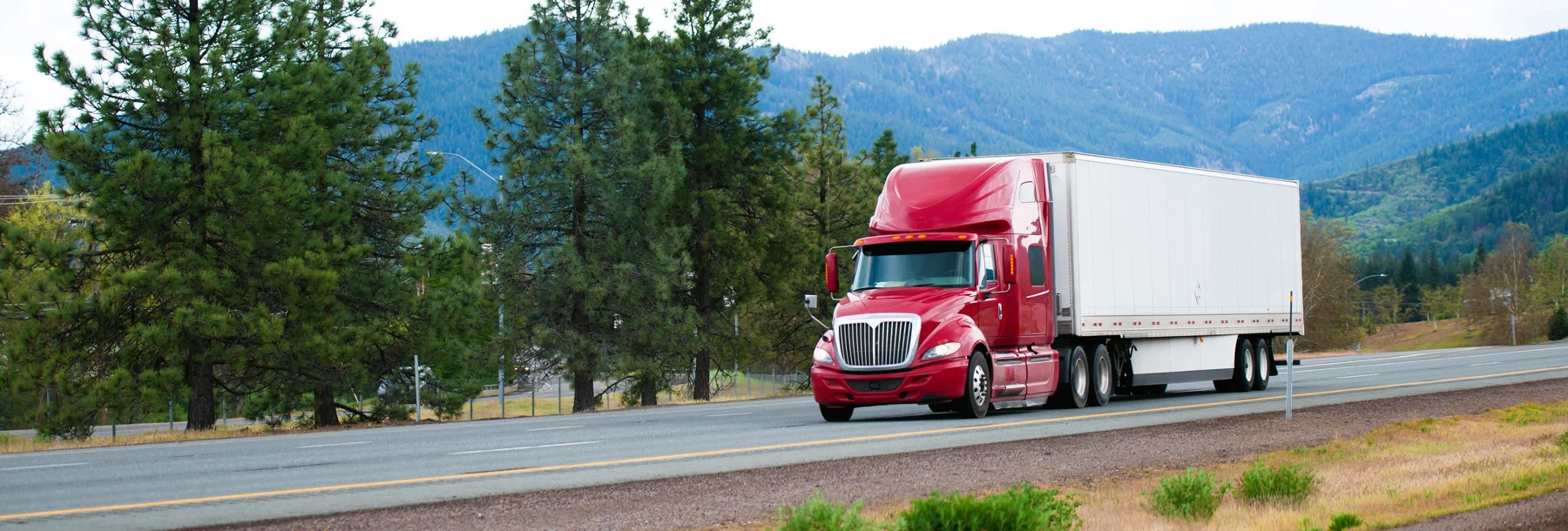 Red Modern Semi Truck with Dry Van Trailer Moving by Divided Highway I-5 in California