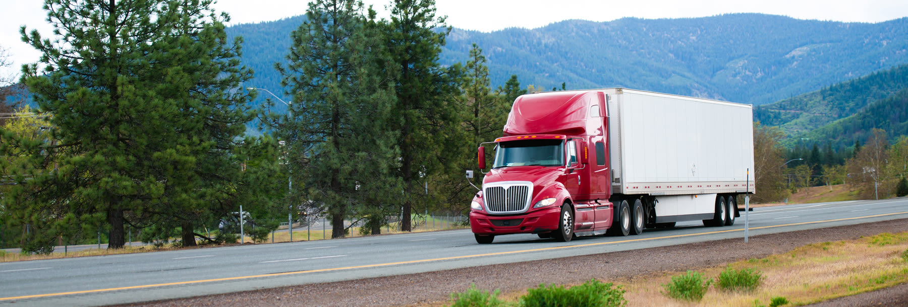 Red Modern Semi Truck with Dry Van Trailer Moving by Divided Highway I-5 in California