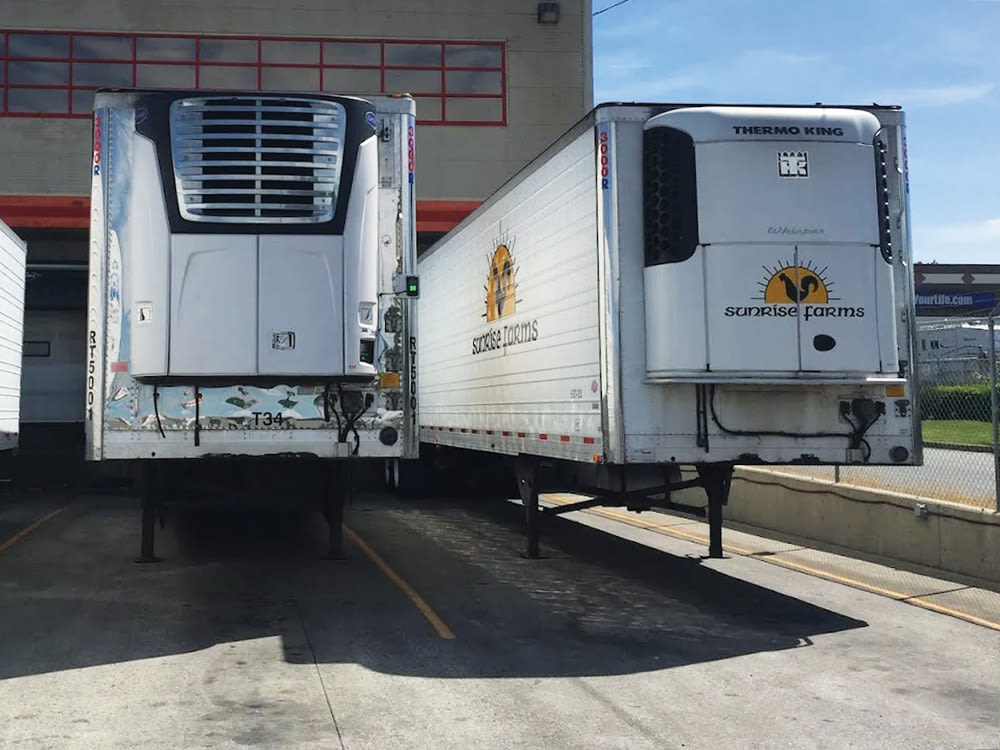 Two Sunrise Farms refrigerated Thermo King trailers docked in yard