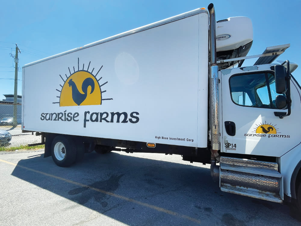 White Sunrise Farms truck with yellow and black logo