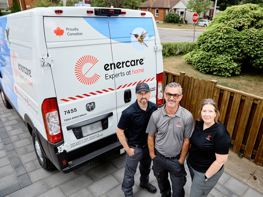 Three Enercare employees standing in front of a branded truck in a residential driveway