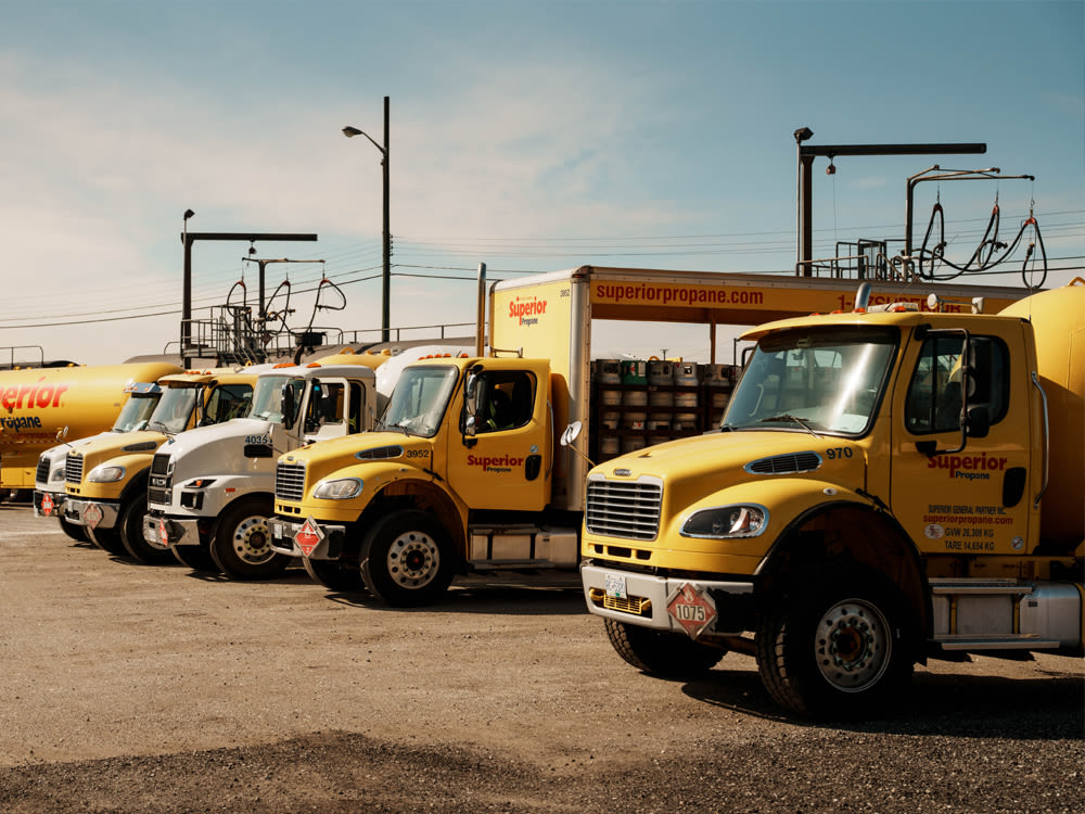 Flotte de camions jaunes Superior Propane stationnés dans une cour, avec réservoirs et équipements de livraison de propane.