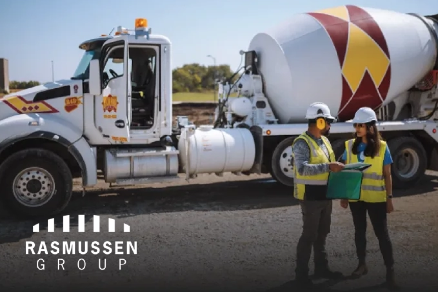 Grupo Rasmussen, dos trabajadores de pie junto a un camión grande con equipo de protección personal