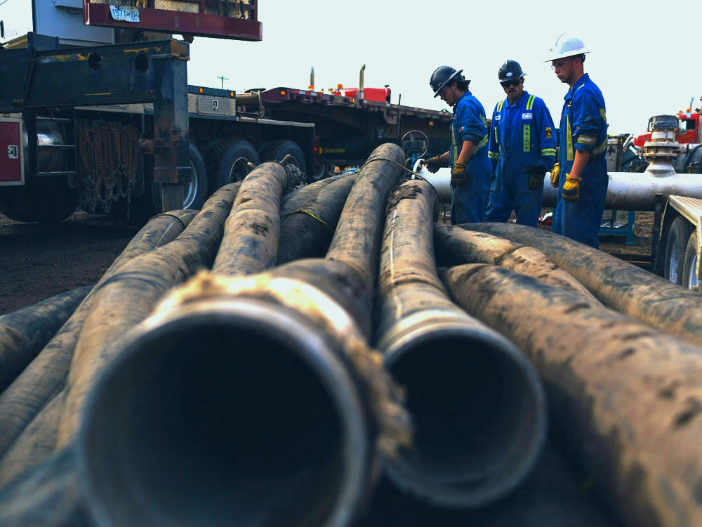 Industrial water pumps in one pile with workers in blue uniforms and hard hats near flatbed trucks for Whitewater Management