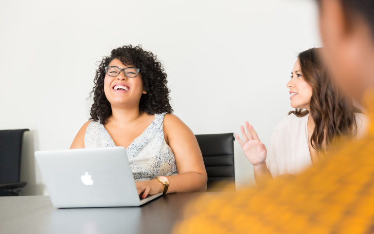 woman laughing at a laptop