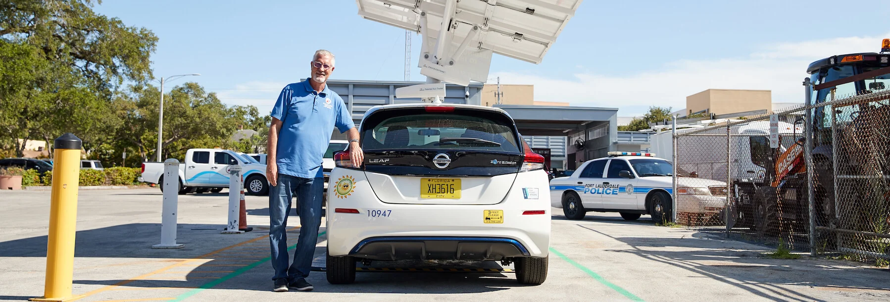 Man with electric vehicle at charging station.