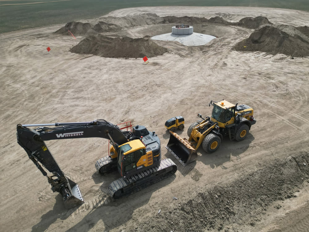 Black and yellow construction equipment on sandy worksite