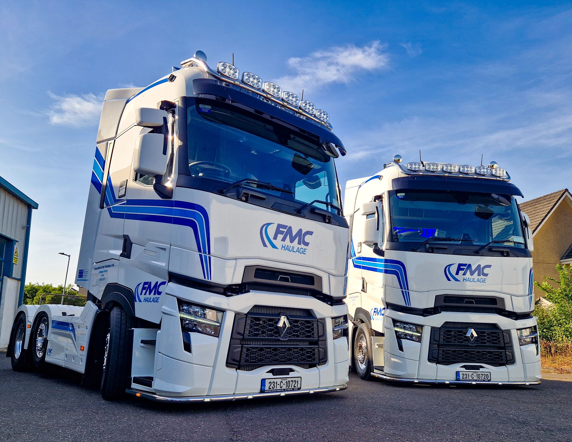 Two white and blue FMC Haulage Renault trucks parked side by side under a blue sky.