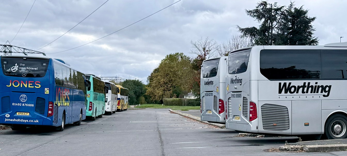 Several coaches parked in a car park, including Jones Holidays blue coach and Worthing Coaches silver coach.