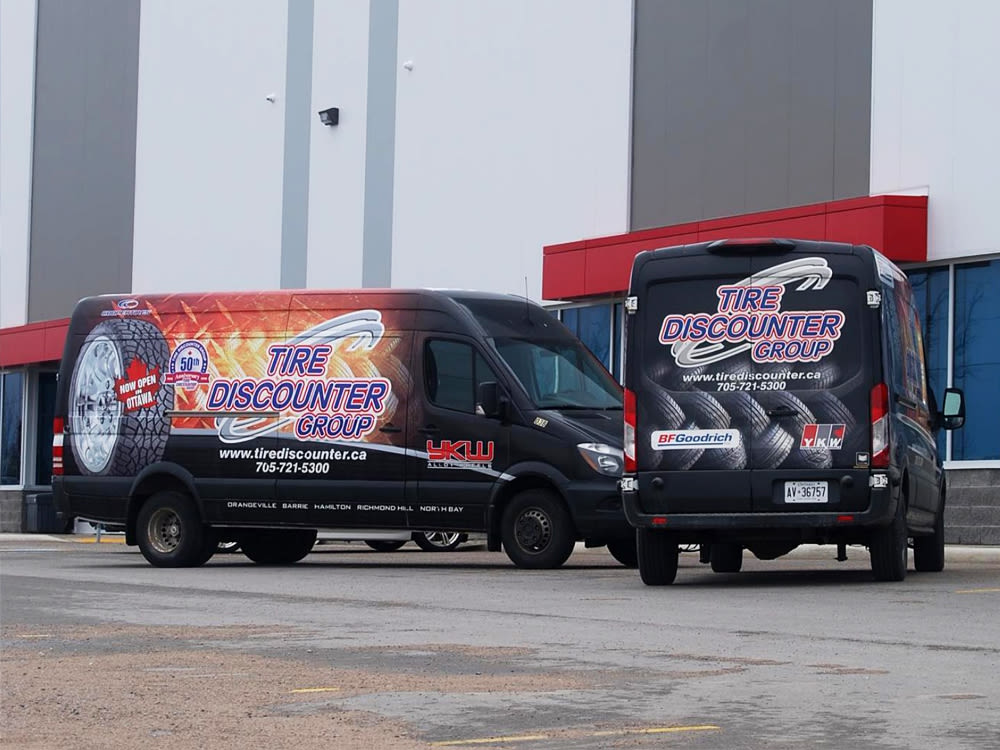 Deux camions de Tire Discounter Group stationnés à l’extérieur de l’entrepôt.
