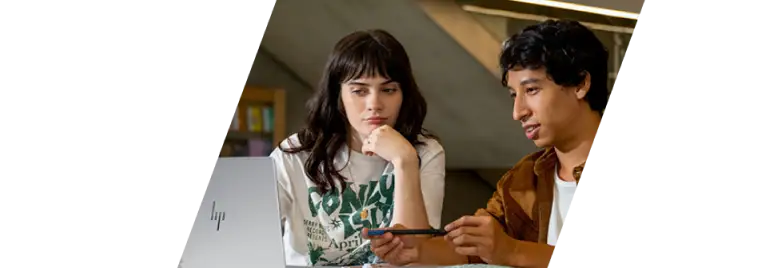 Two people looking at an HP laptop