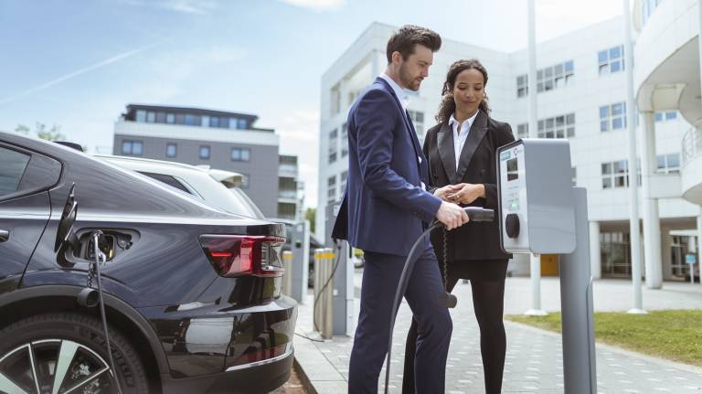 Man and woman in suits charging black EV