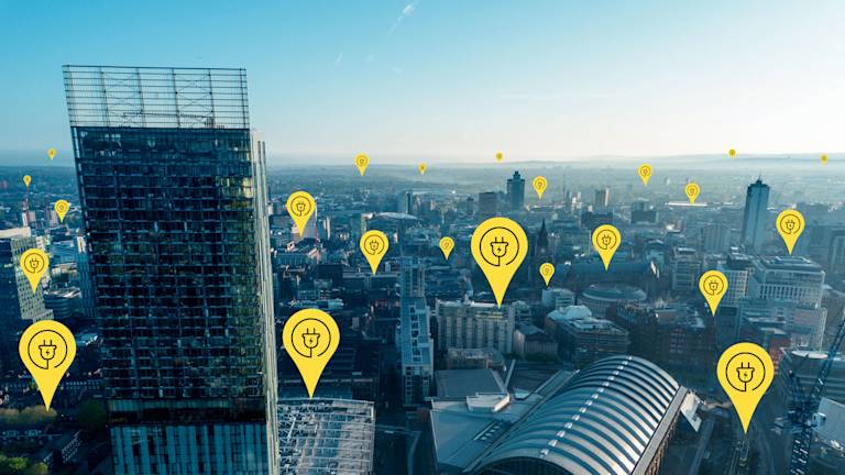 Electric charge point icons dotted across the Manchester skyline