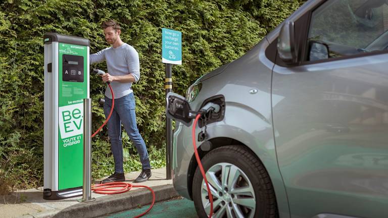 Man charging silver van at Be.EV charger