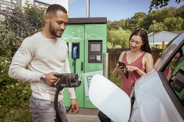 Man and woman charging an electric car