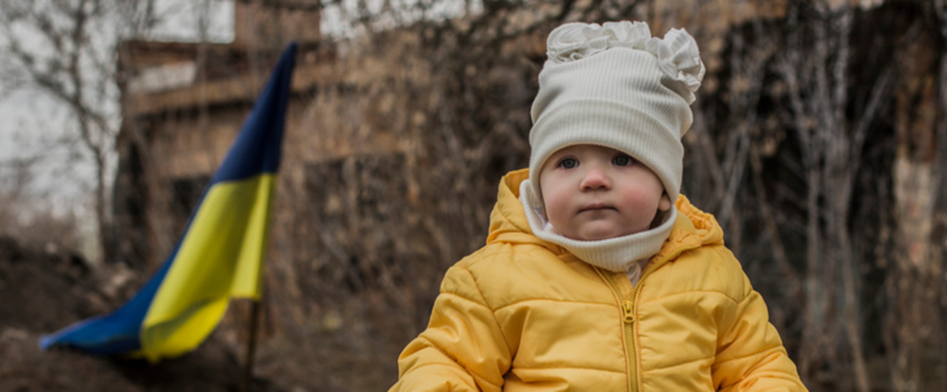 Kleines Mädchen vor Verteidigungsanlagen der ukrainischen Armee. Krieg in der Ukraine. Kinder und Krieg. Unterstützung für die Ukraine. Stoppt den Krieg. Humanitäre Katastrophe. Ukrainische Flagge.