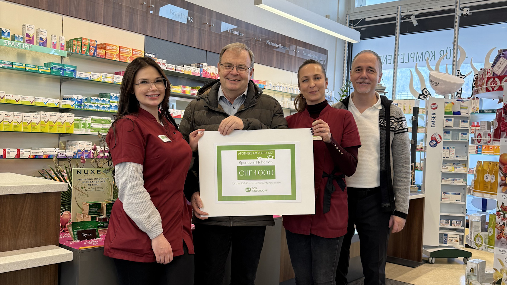 Kristina Lang (Mitarbeiterin Apotheke), Markus Schaper (SOS-Kinderdorf), Ula Ziet-ka (Mitarbeiterin Apotheke), Nikolaus Frick (Inhaber Apotheke) bei der Checkübergabe in der Apotheke am Postplatz in Schaan