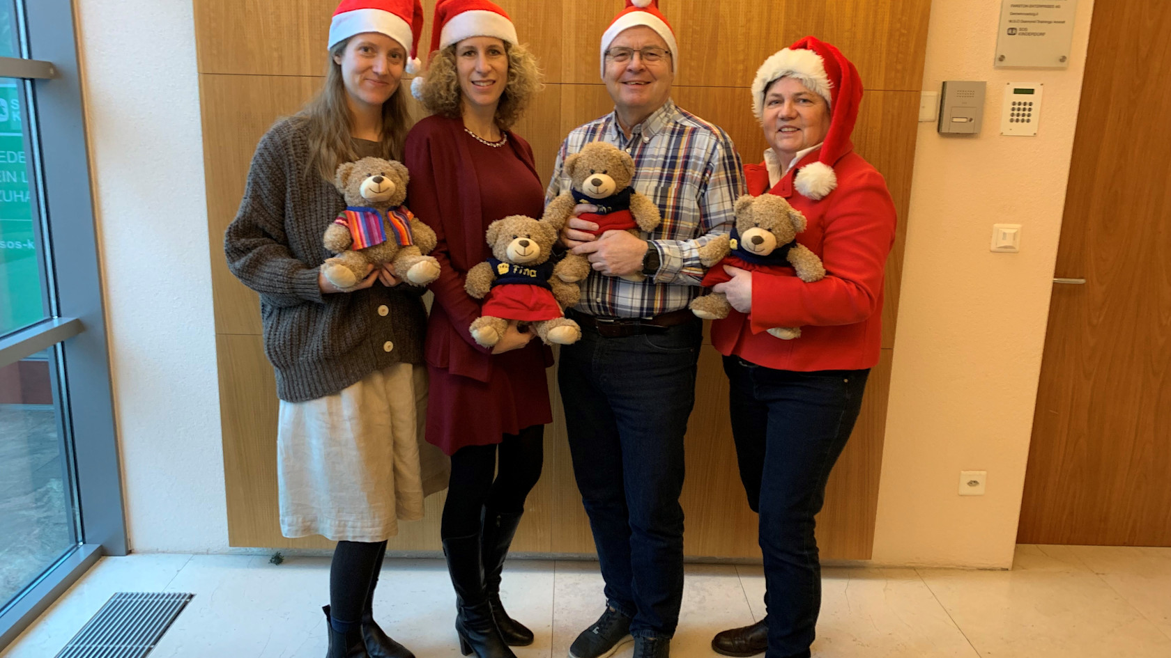 Das SOS-Kinderdorf Liechtenstein Team mit Weihnachtsmützen und den Teddybären Finn und Fina.