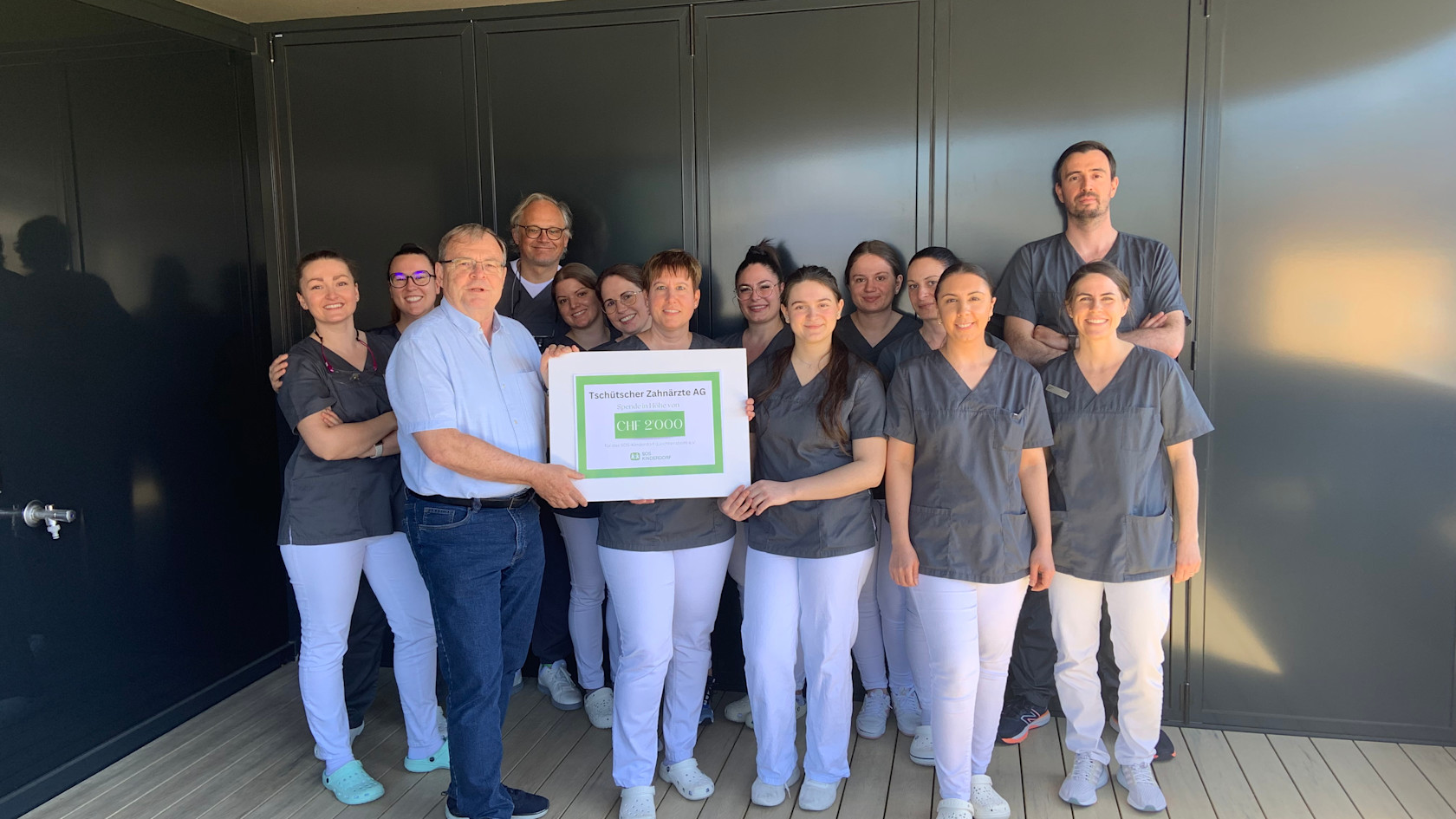 Checkübergabe bei Tschütscher Zahnärzte im April 2025 mit dem ganzen Team auf dem Bild sowie Markus Schaper von SOS-Kinderdorf mit dem Check