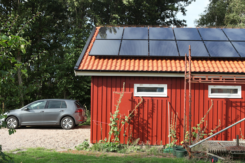 Elbil bredvid ett garage med solceller på taket.
