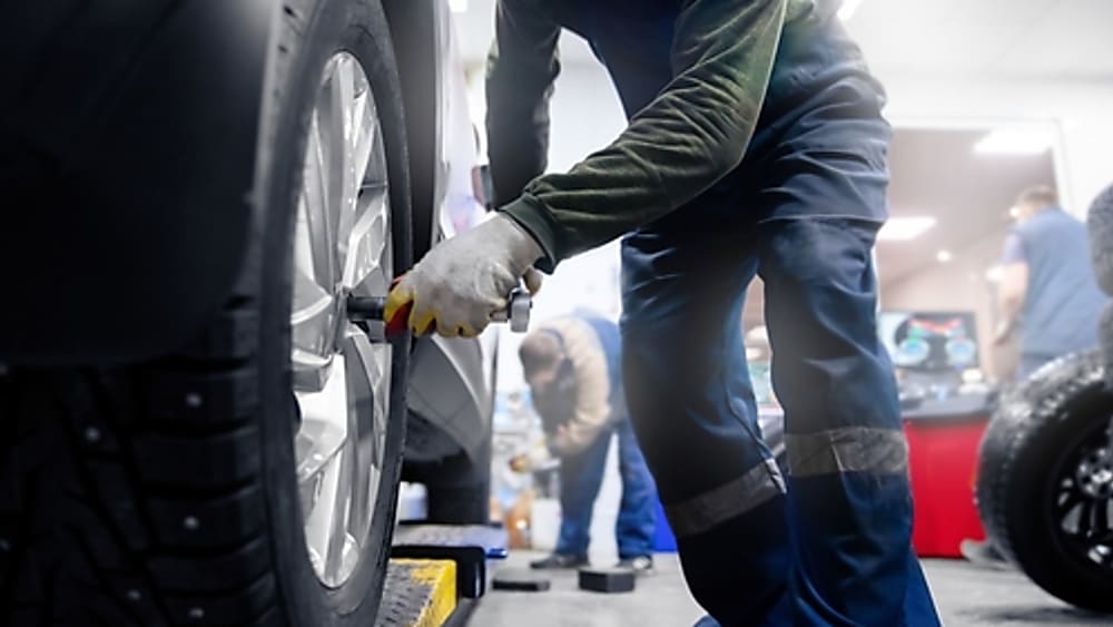 A tire technician tightening on new studded winter tires