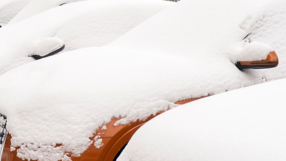 Orange vehicle parked and covered in snow