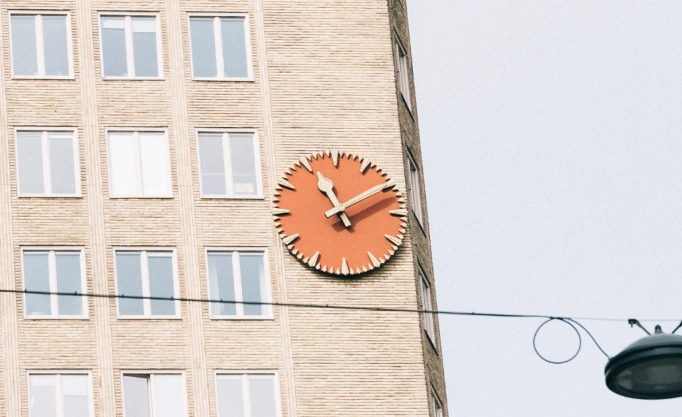 This image depicts a close up of a building displaying a large clock, connoting the urgency of time passing.
