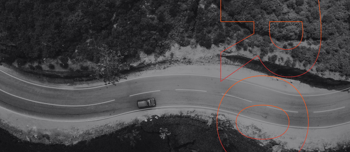 Seen from above, a car drives on a curving road.